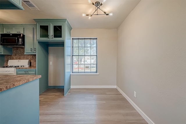 kitchen featuring white range with gas stovetop, tasteful backsplash, green cabinetry, an inviting chandelier, and light hardwood / wood-style flooring