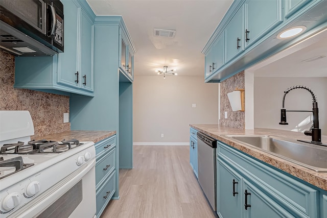 kitchen featuring a sink, blue cabinets, light countertops, and gas range gas stove