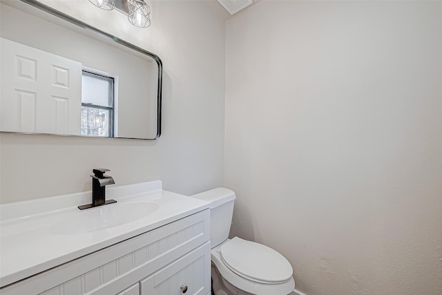 half bath with toilet, visible vents, and vanity