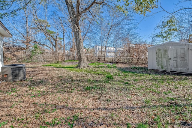 view of yard featuring central AC, an outdoor structure, a fenced backyard, and a storage shed