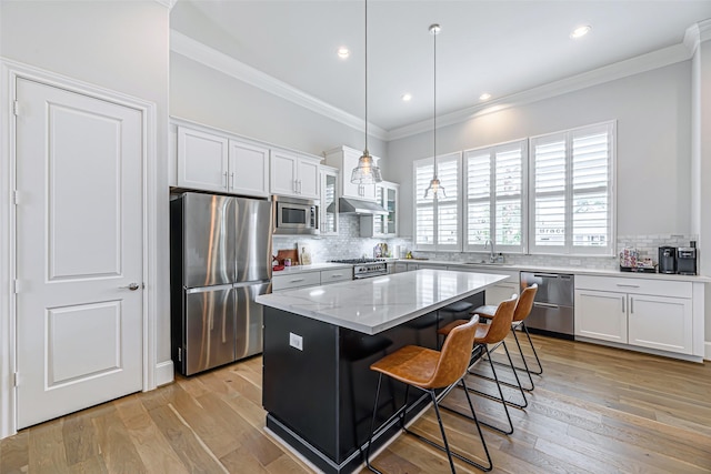 kitchen featuring decorative light fixtures, white cabinetry, stainless steel appliances, and a kitchen island