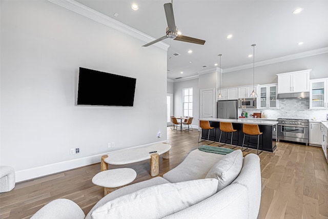 living room featuring ceiling fan, crown molding, and light hardwood / wood-style floors