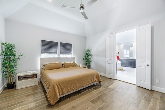 bedroom with ceiling fan, connected bathroom, vaulted ceiling, and wood-type flooring