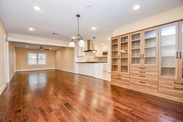 unfurnished living room featuring hardwood / wood-style flooring, sink, and ceiling fan