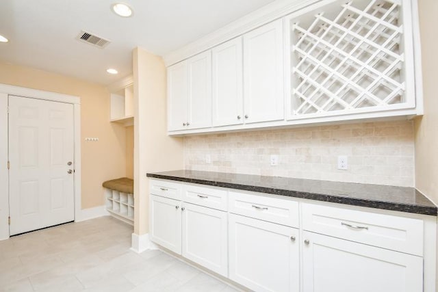 kitchen featuring decorative backsplash, white cabinets, and dark stone countertops