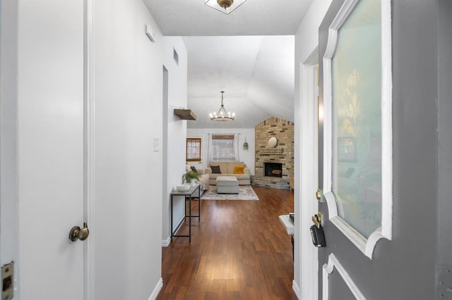 corridor featuring visible vents, a notable chandelier, dark wood-style floors, baseboards, and vaulted ceiling