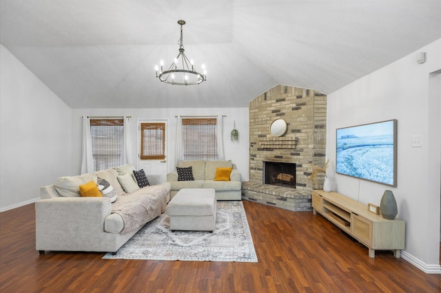 living room with lofted ceiling, a brick fireplace, dark hardwood / wood-style floors, and a chandelier