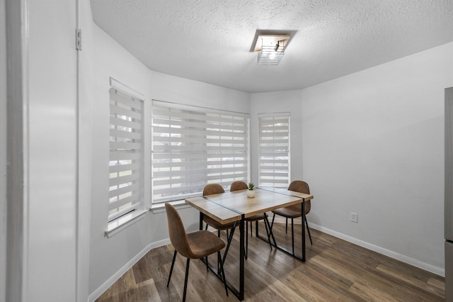 dining space with dark hardwood / wood-style floors and a textured ceiling