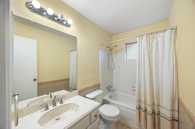 full bathroom with shower / tub combo with curtain, tile walls, vanity, a textured ceiling, and toilet