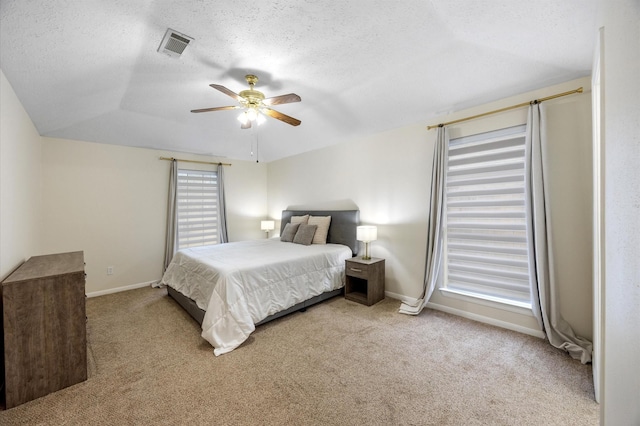 carpeted bedroom featuring ceiling fan, a tray ceiling, vaulted ceiling, and a textured ceiling