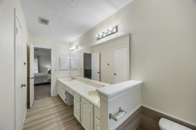 bathroom with hardwood / wood-style flooring, vanity, a textured ceiling, and toilet