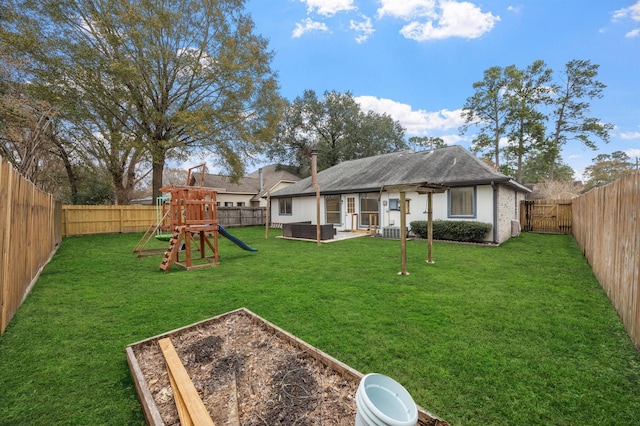 view of yard featuring a garden, a fenced backyard, and a playground