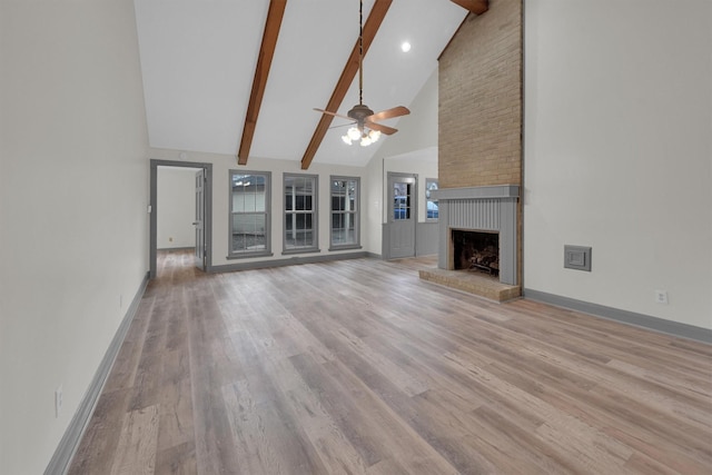 unfurnished living room with beam ceiling, high vaulted ceiling, light wood-type flooring, ceiling fan, and a fireplace