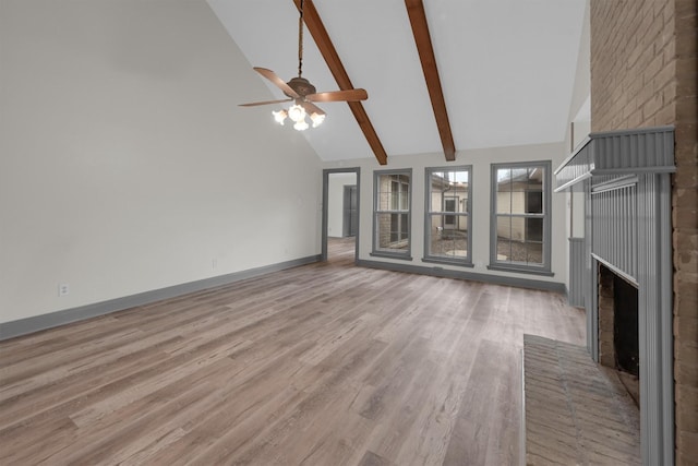 unfurnished living room featuring high vaulted ceiling, a brick fireplace, beamed ceiling, ceiling fan, and light hardwood / wood-style floors