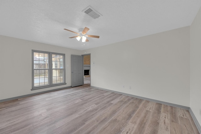 empty room featuring ceiling fan, a textured ceiling, and light hardwood / wood-style floors