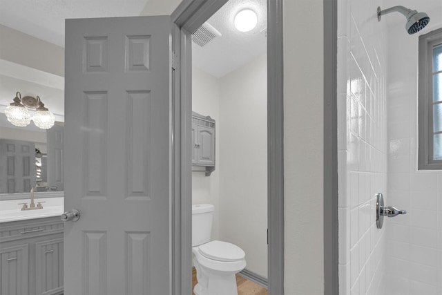 bathroom featuring vanity, tiled shower, and toilet