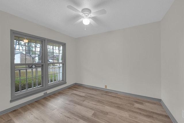 empty room featuring ceiling fan, light hardwood / wood-style flooring, and a textured ceiling