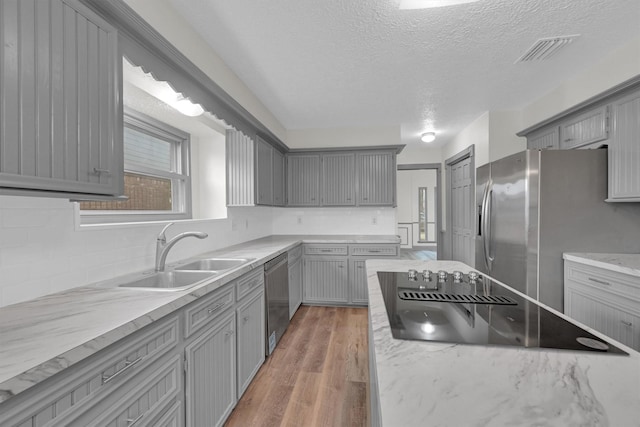 kitchen featuring appliances with stainless steel finishes, hardwood / wood-style floors, sink, gray cabinetry, and decorative backsplash