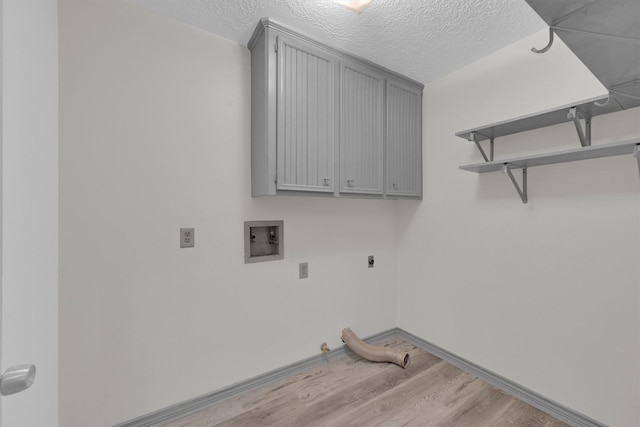 washroom featuring gas dryer hookup, cabinets, hookup for a washing machine, a textured ceiling, and light hardwood / wood-style flooring