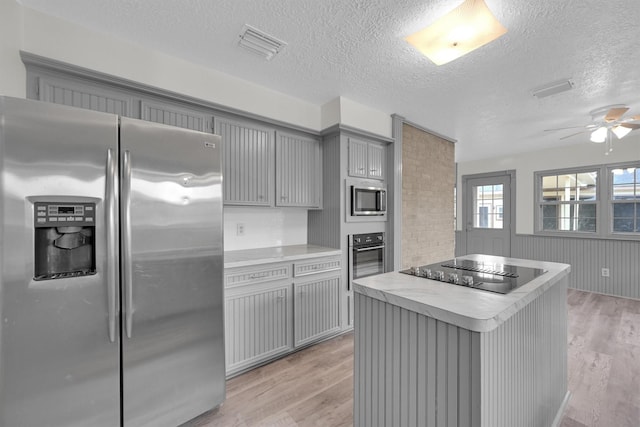 kitchen with stainless steel appliances, gray cabinets, a textured ceiling, and light hardwood / wood-style flooring