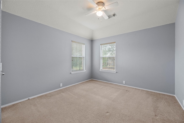 spare room with lofted ceiling, a textured ceiling, light colored carpet, and ceiling fan