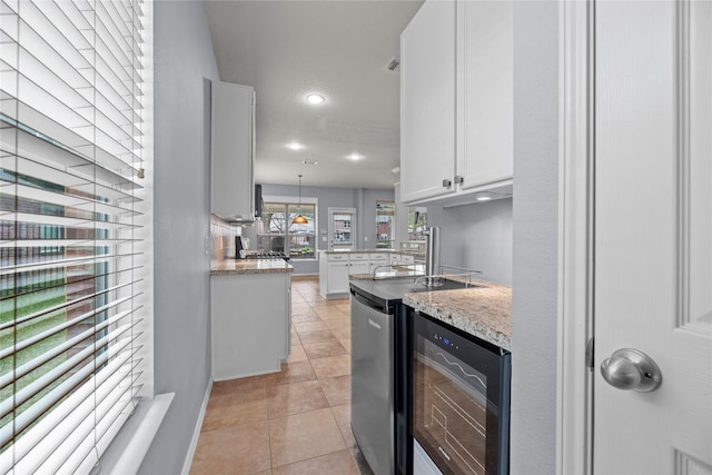 kitchen featuring white cabinetry, hanging light fixtures, wine cooler, light stone counters, and light tile patterned flooring