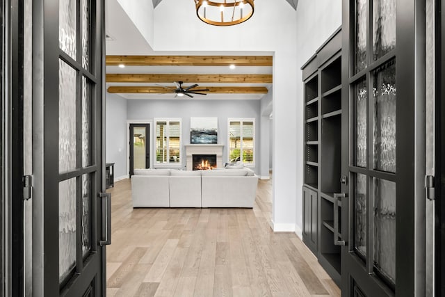 interior space with built in shelves, light hardwood / wood-style floors, and beamed ceiling