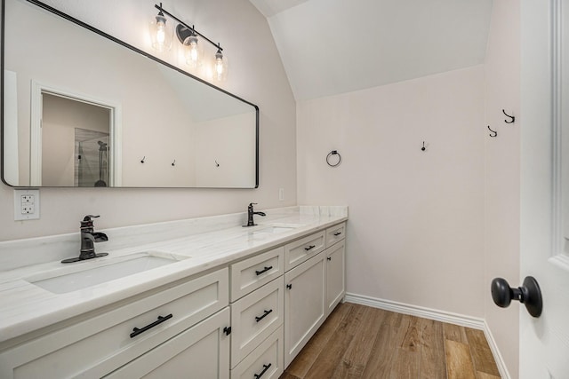 bathroom featuring hardwood / wood-style flooring, lofted ceiling, walk in shower, and vanity