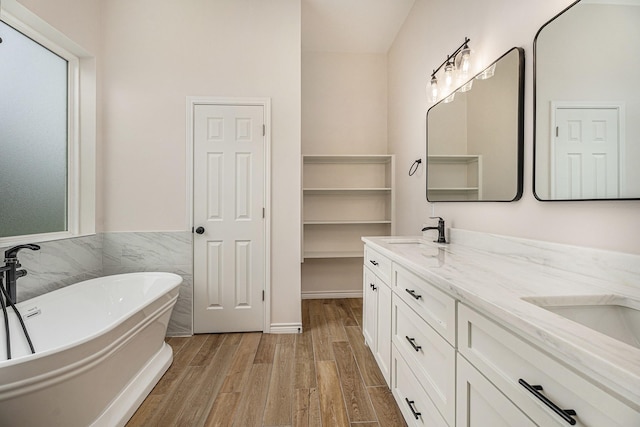 bathroom featuring hardwood / wood-style flooring, vanity, tile walls, and a bathtub