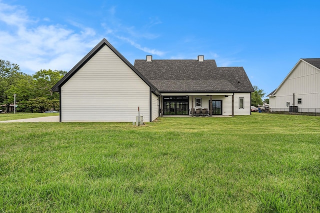 rear view of property featuring cooling unit and a lawn