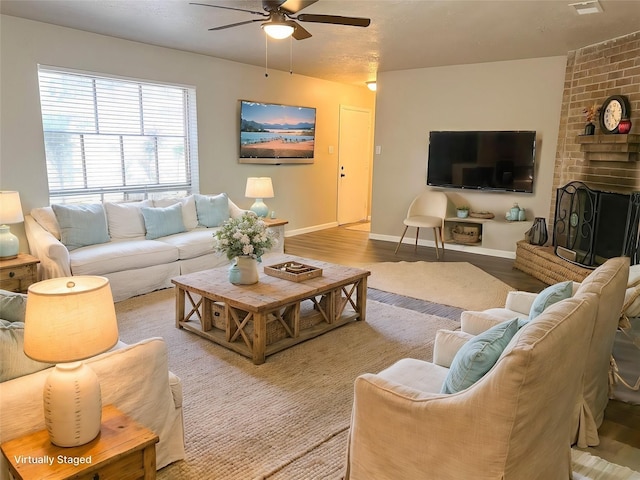 living room featuring ceiling fan, a fireplace, and light wood-type flooring