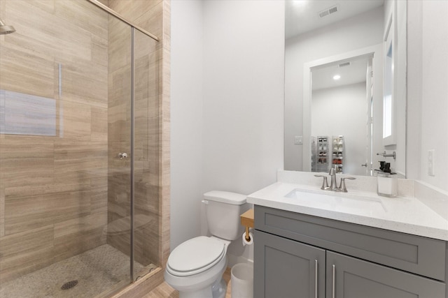 bathroom featuring vanity, toilet, and a shower with door