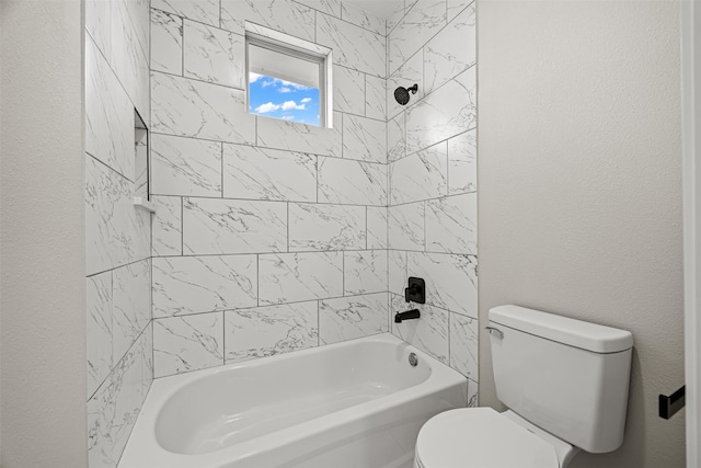 bathroom featuring tiled shower / bath combo and toilet