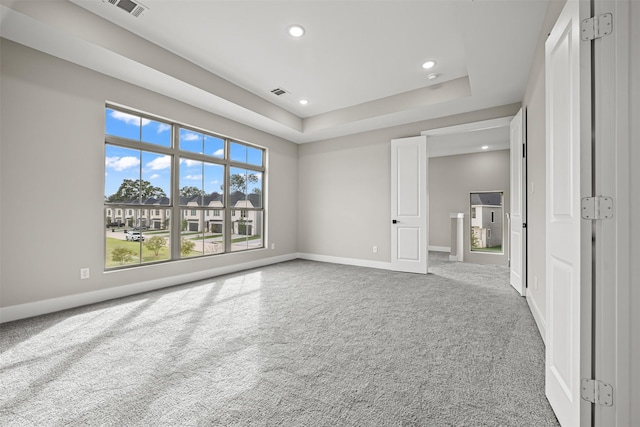 spare room featuring a tray ceiling and carpet flooring