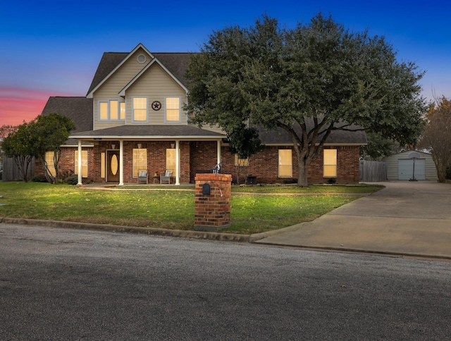 view of front of house featuring a lawn, a porch, and a storage unit