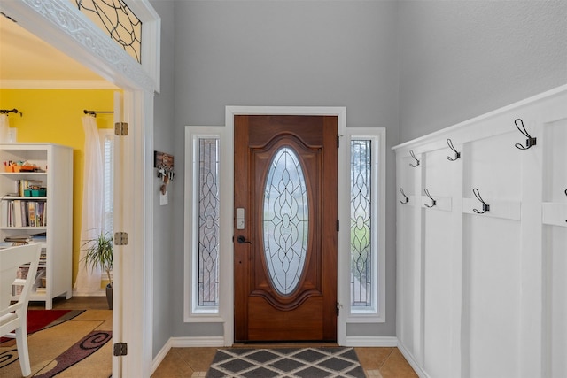 entryway with ornamental molding, plenty of natural light, and light tile patterned floors