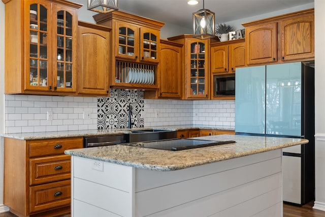 kitchen with pendant lighting, sink, light stone countertops, black appliances, and decorative backsplash