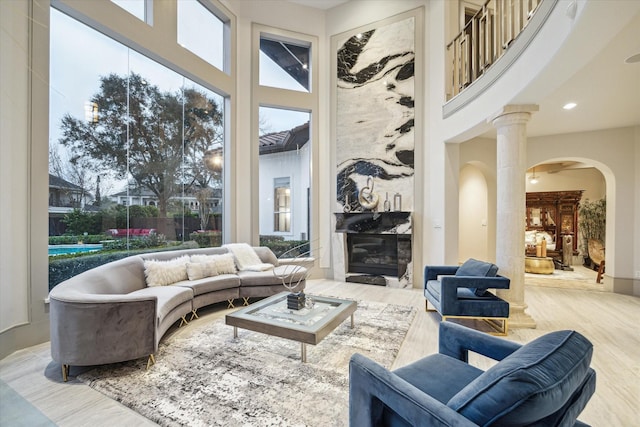 sunroom / solarium with light wood-type flooring, ornate columns, and a high ceiling