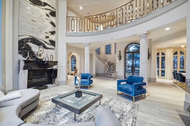 living room with decorative columns, a towering ceiling, and a fireplace