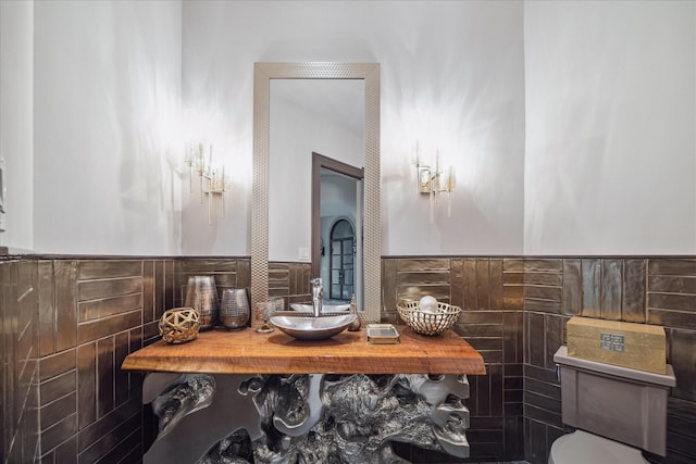 bathroom featuring sink, tile walls, and toilet