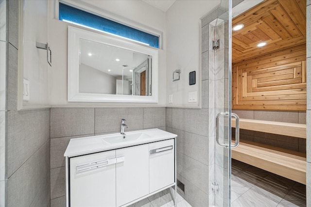 bathroom featuring vanity, an enclosed shower, and tile walls