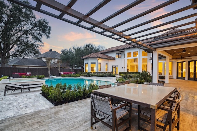 pool at dusk featuring a diving board, a patio area, ceiling fan, and a pergola