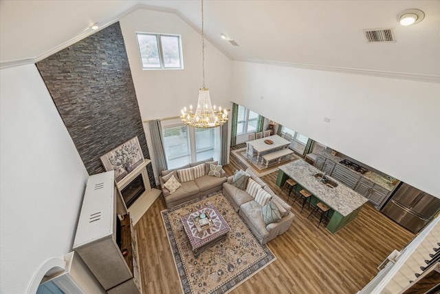 living room with a notable chandelier, a fireplace, high vaulted ceiling, and a wealth of natural light