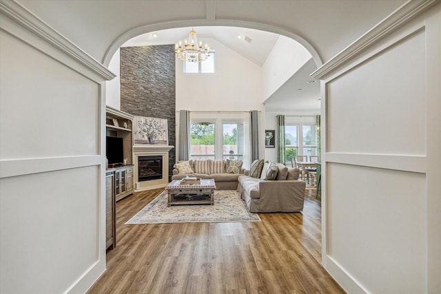 living room featuring lofted ceiling, a large fireplace, and light wood-type flooring