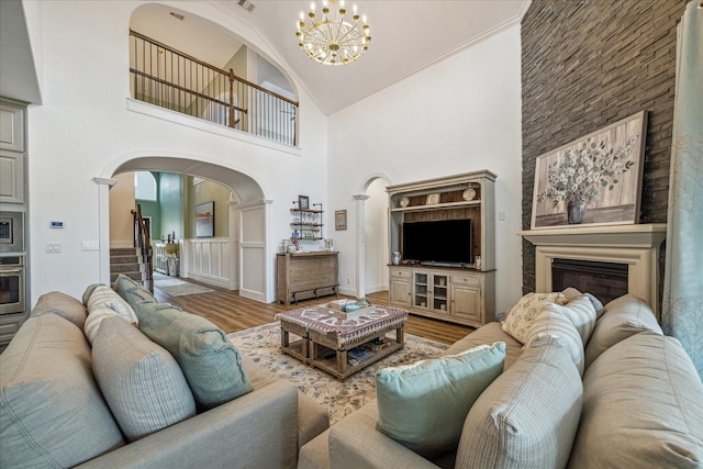 living room featuring hardwood / wood-style flooring, ornamental molding, high vaulted ceiling, and a notable chandelier