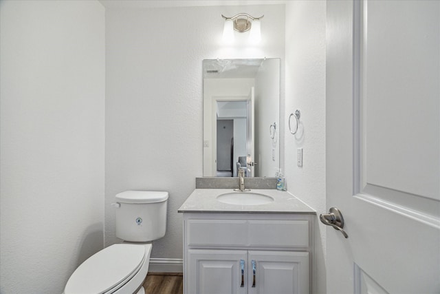 bathroom with hardwood / wood-style flooring, vanity, and toilet