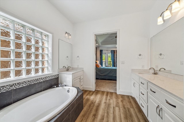 bathroom with hardwood / wood-style flooring, vanity, and a relaxing tiled tub