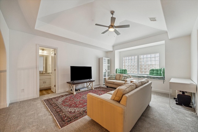 living room featuring light carpet, a tray ceiling, and ceiling fan