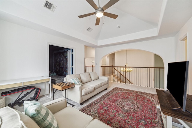 living room featuring ceiling fan with notable chandelier, high vaulted ceiling, and a tray ceiling