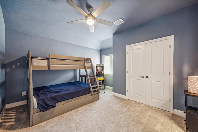 carpeted bedroom featuring ceiling fan, vaulted ceiling, and a closet